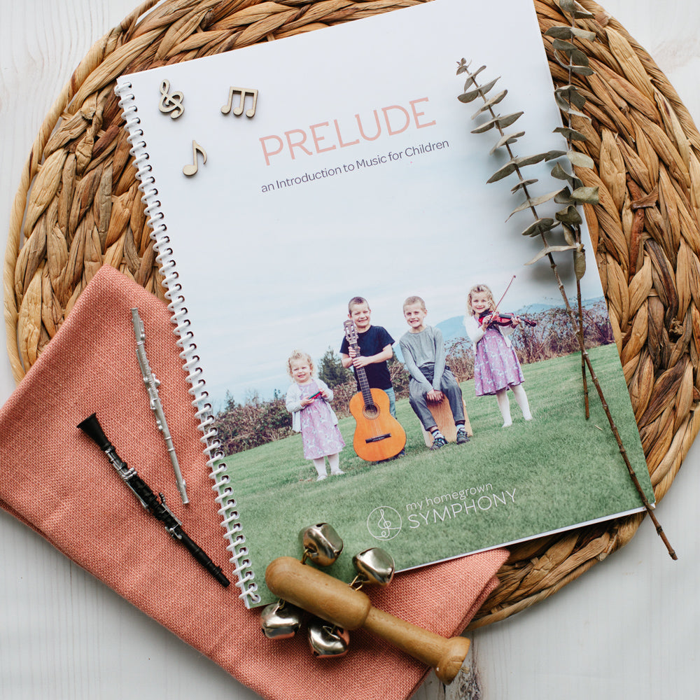 a spiral bound music curriculum featuring a cover with the title PRELUDE and an image of four smiling children holding instruments